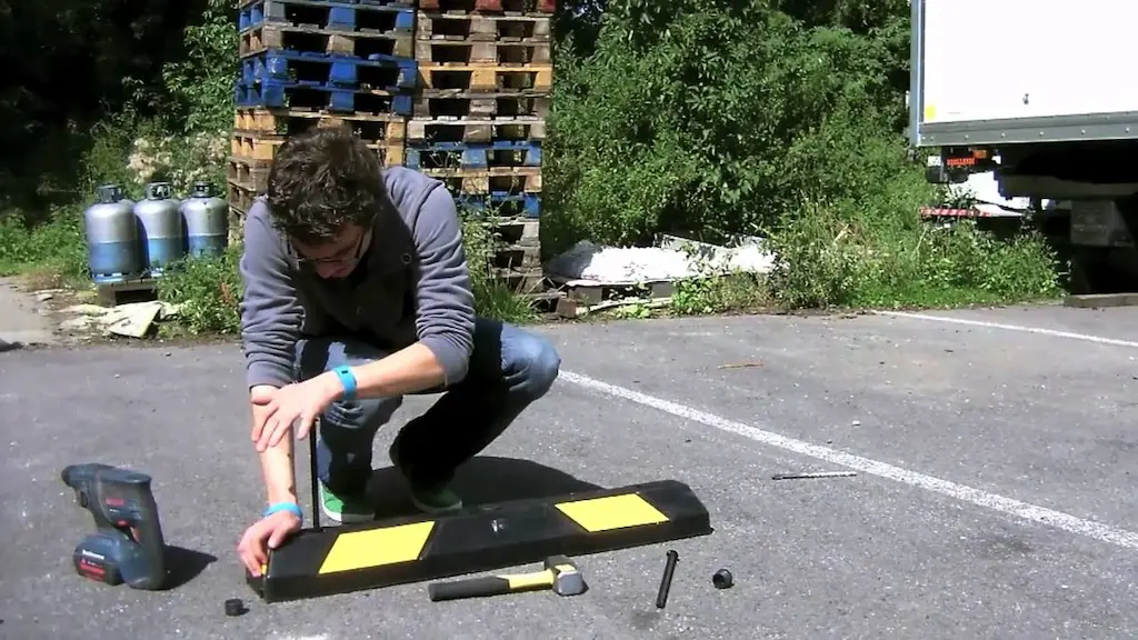 A black and yellow wheel stop is being installed on the ground.