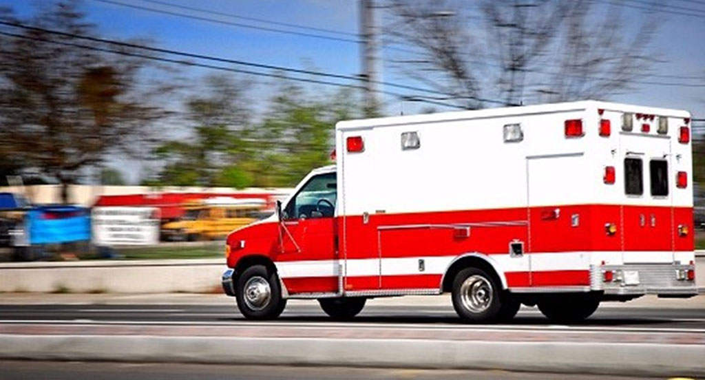 A white and red ambulance on the road.