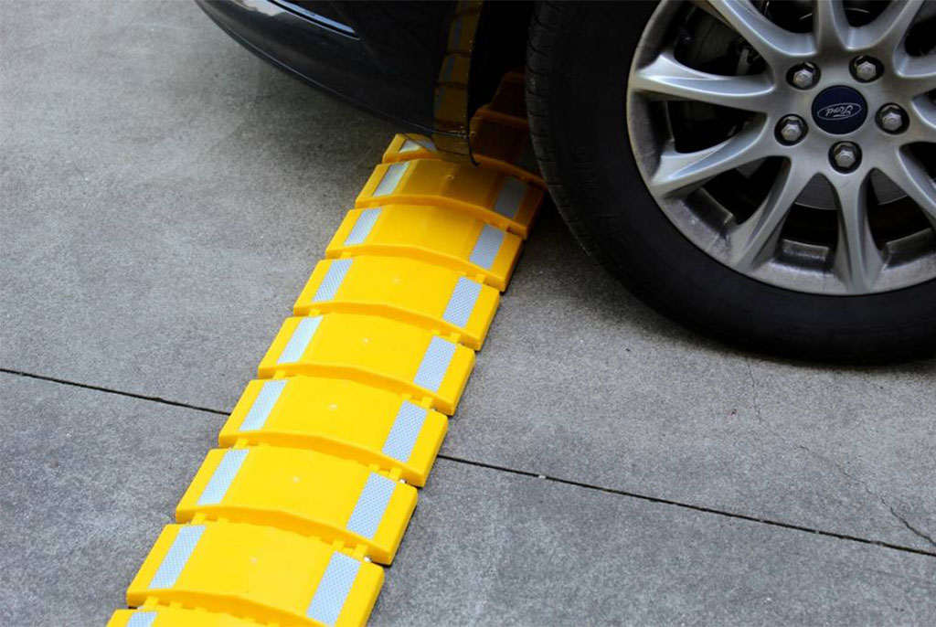 A yellow portable speed bump with reflective films to increase visibility.